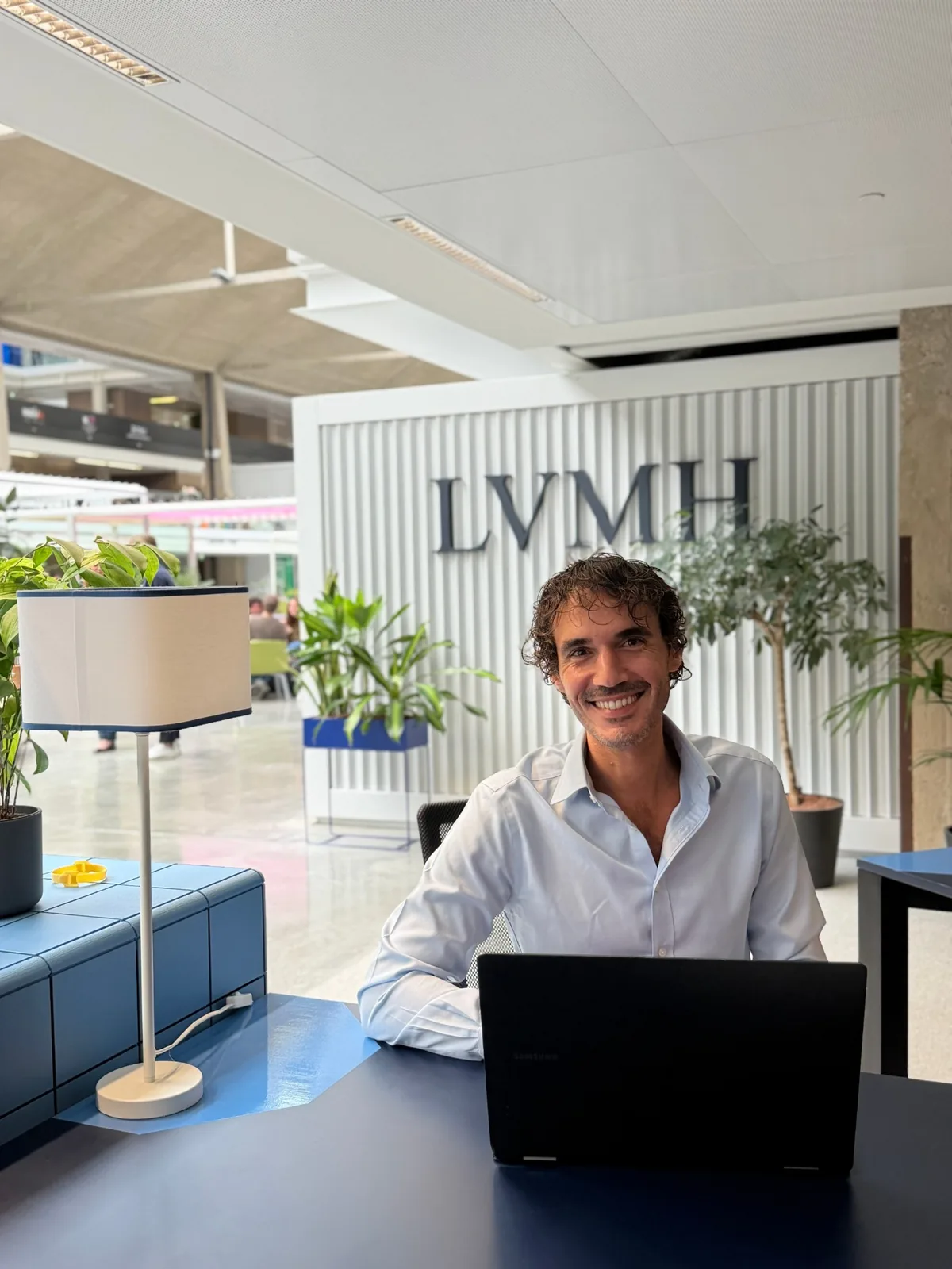Virgile à son bureau, à côté du logo LVMH